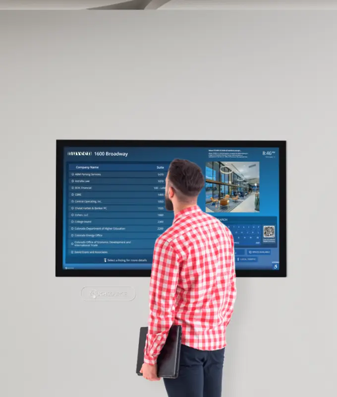Tenant using an interactive digital lobby display to view company listings, suite numbers, and building information designed to improve communication and tenant satisfaction.